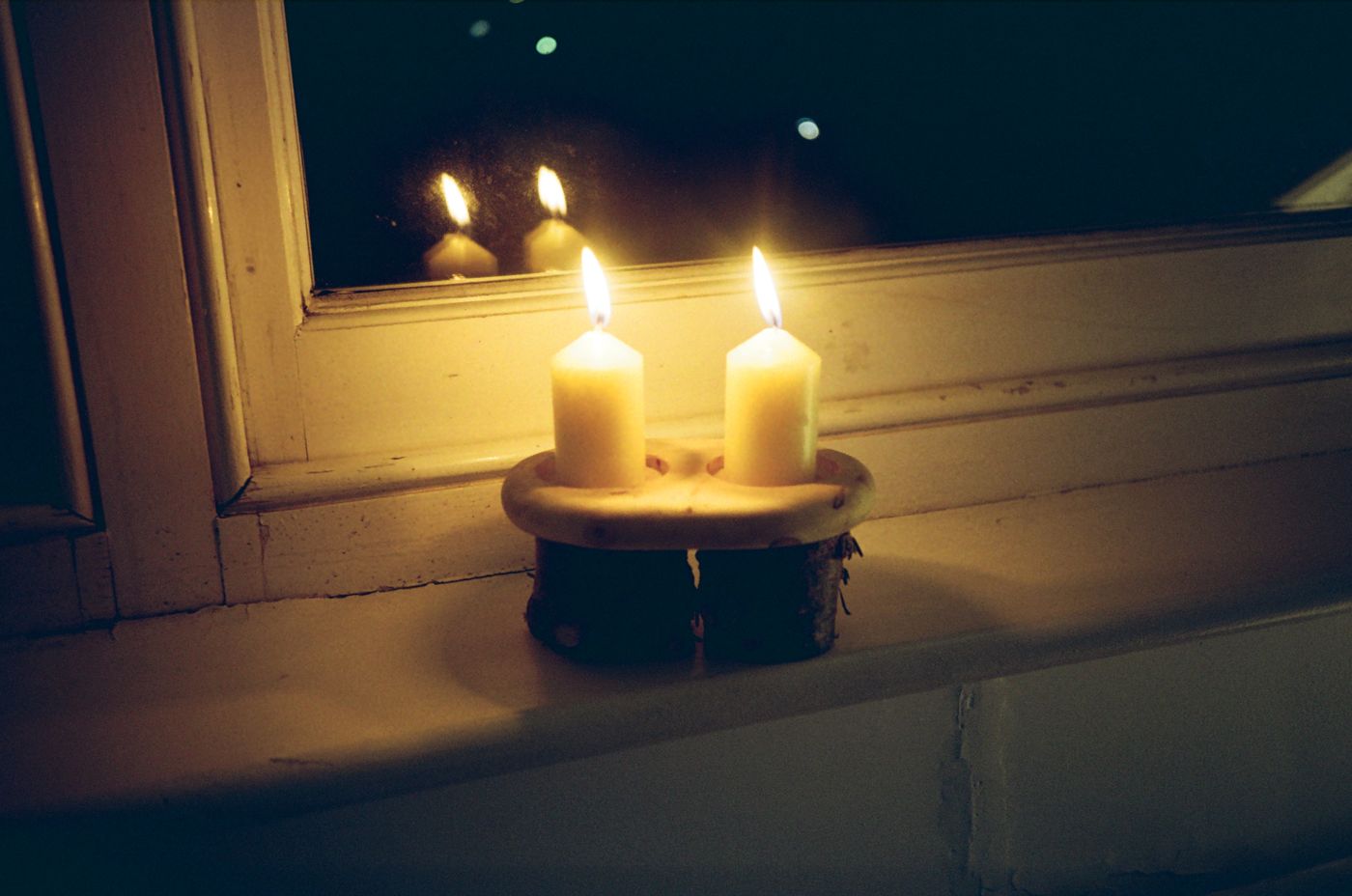 Christmas tree variation, two candles lit on a window sill at night