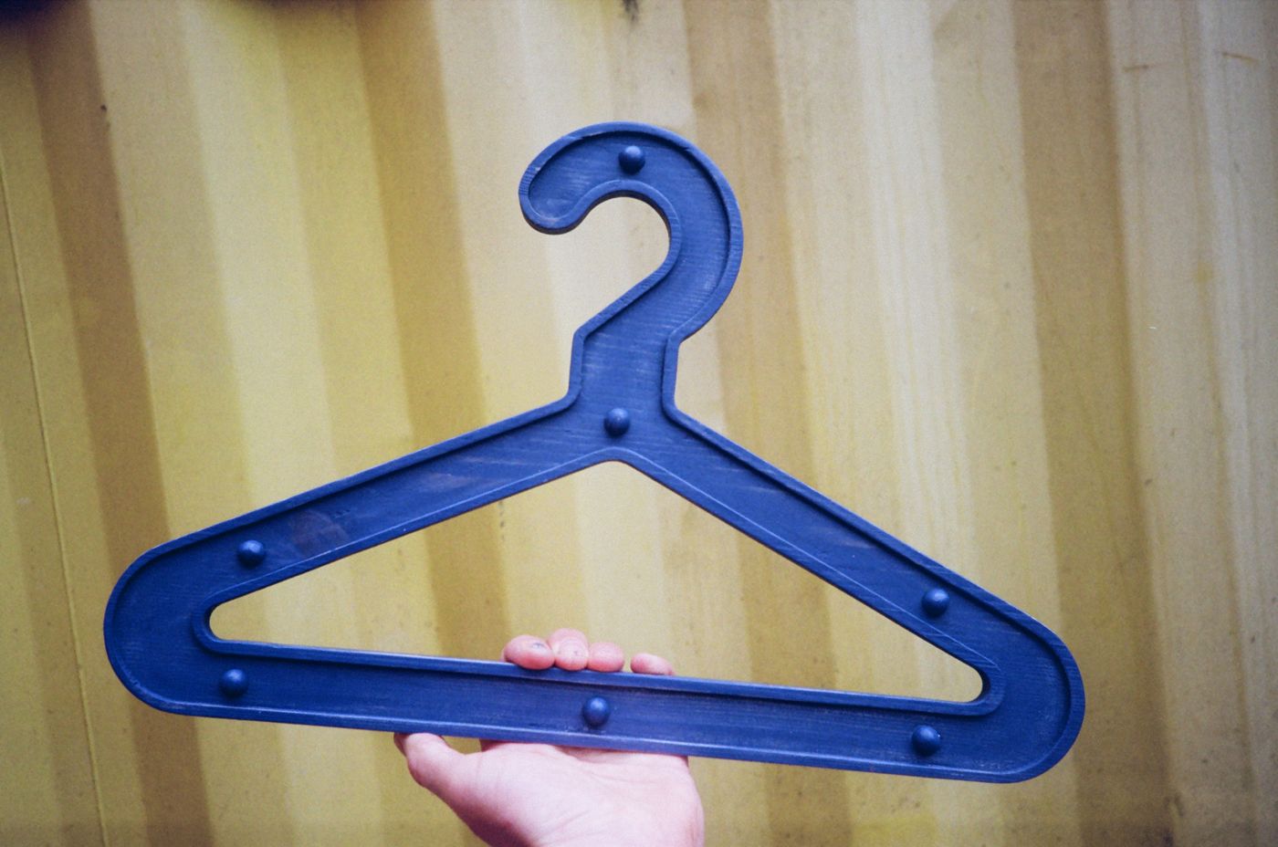 Blue Girder Hanger held up against a yellow shipping container
