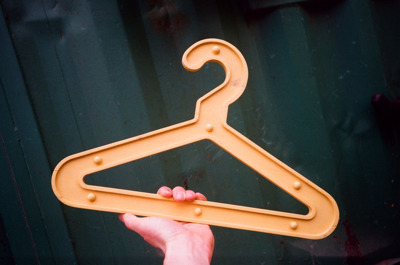 Yellow Girder Hanger held up against a green shipping container