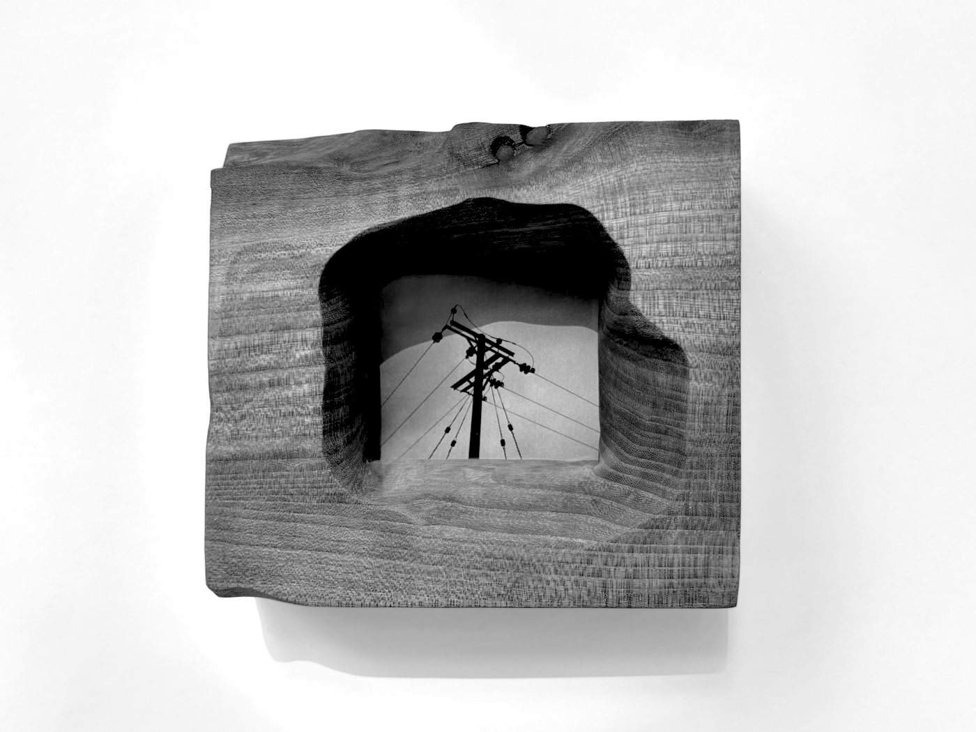 Offcut Frame in ash, its carved opening framing a photograph of tower blocks and cranes
