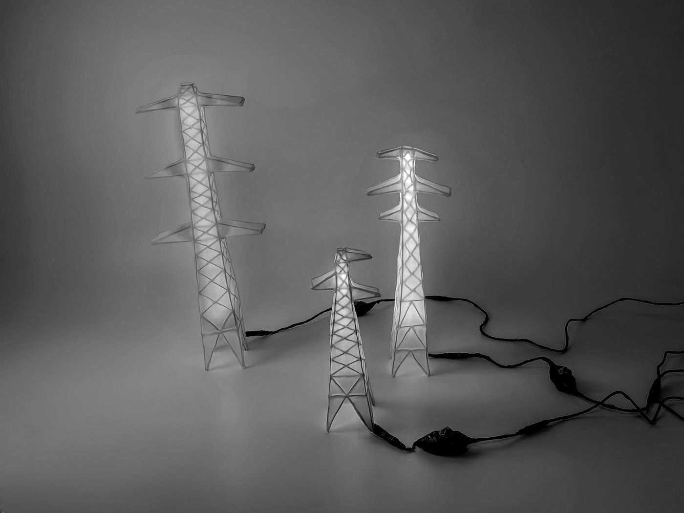 Three glowing pylon-shaped lamps made from masking tape and craft wire, linked by taped cables
