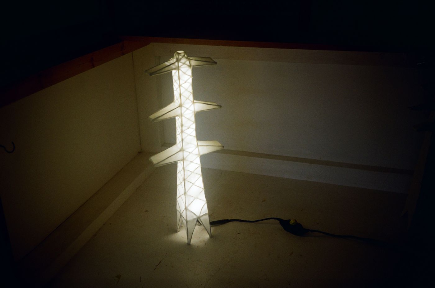 Tallest Pylon Lamp with three arms glowing, its cable trailing across the floor
