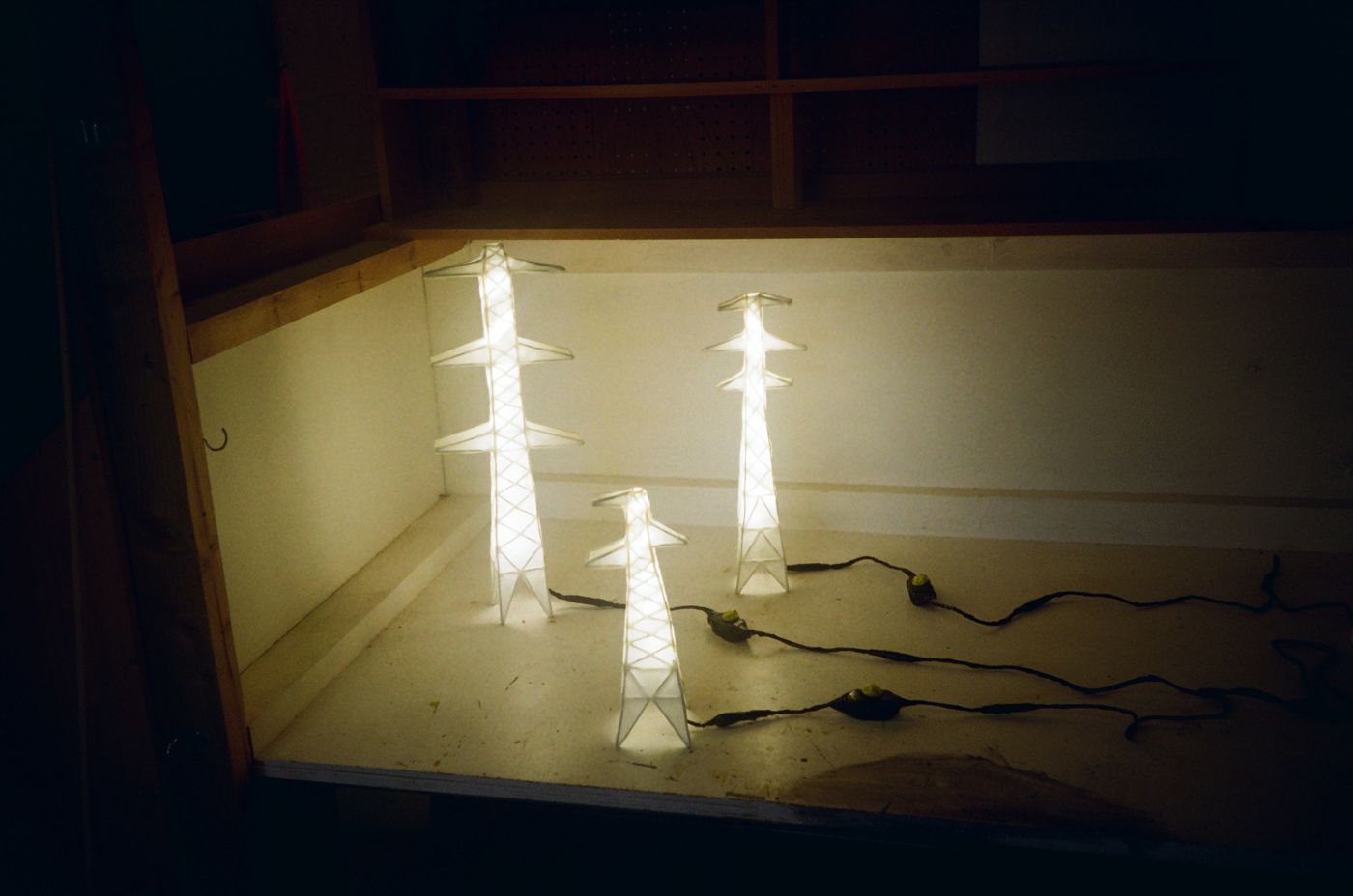 Three Pylon Lamps of different heights lit together, cables and switches across the floor